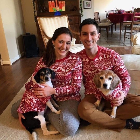 Ian and Sara, and their dogs Annabelle and Luna, all dressed in matching jumpers.